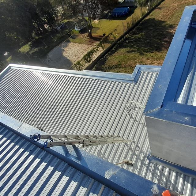 Rufos e calhas pintados de azul em telhado metálico