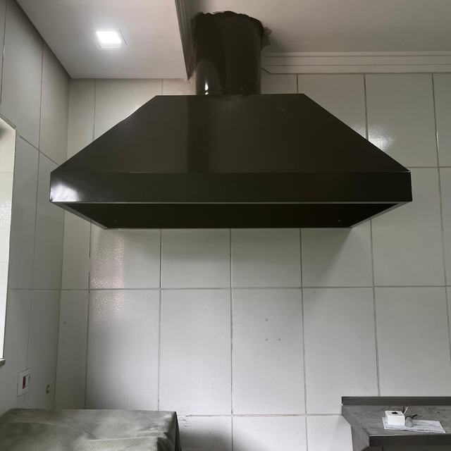 Coifa escura instalada em cozinha azulejada