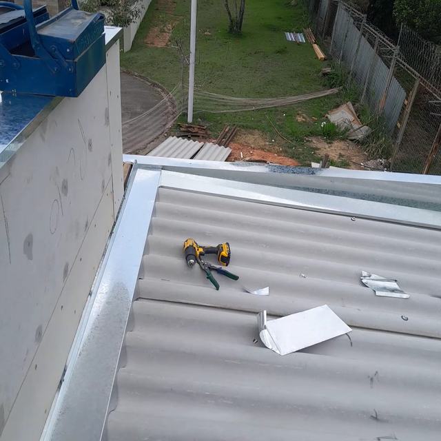 Rufo galvanizado sendo instalado sobre telhado de fibrocimento